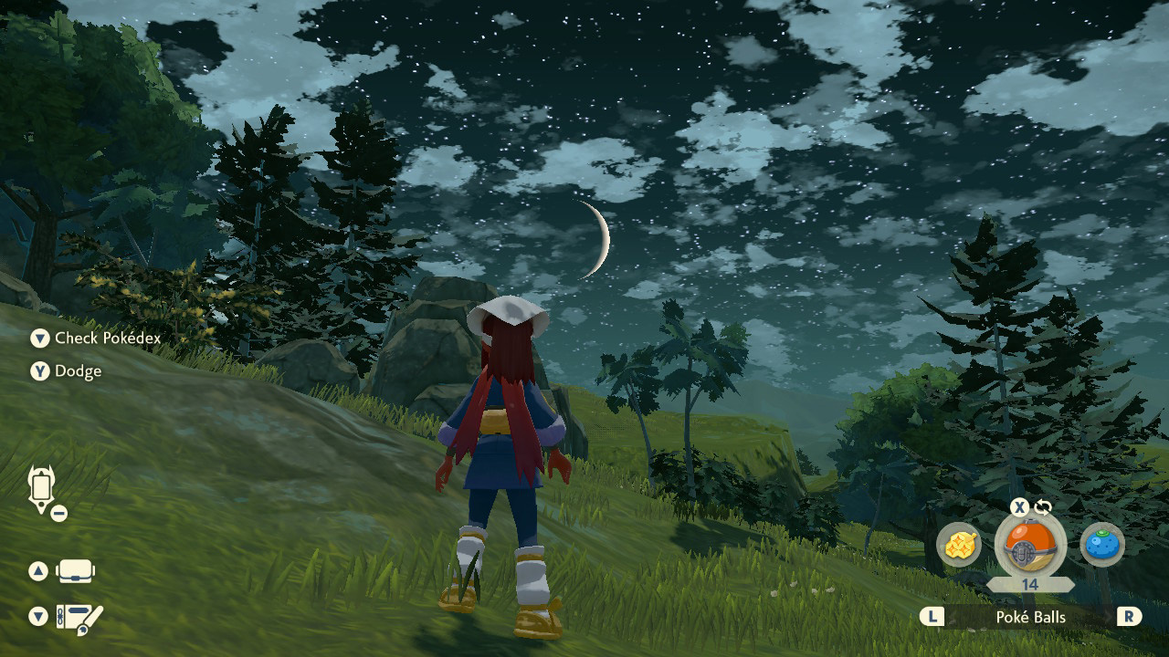 A girl stands on a rocky hillside at night. The moon is just a sliver that hangs low on the horizon.